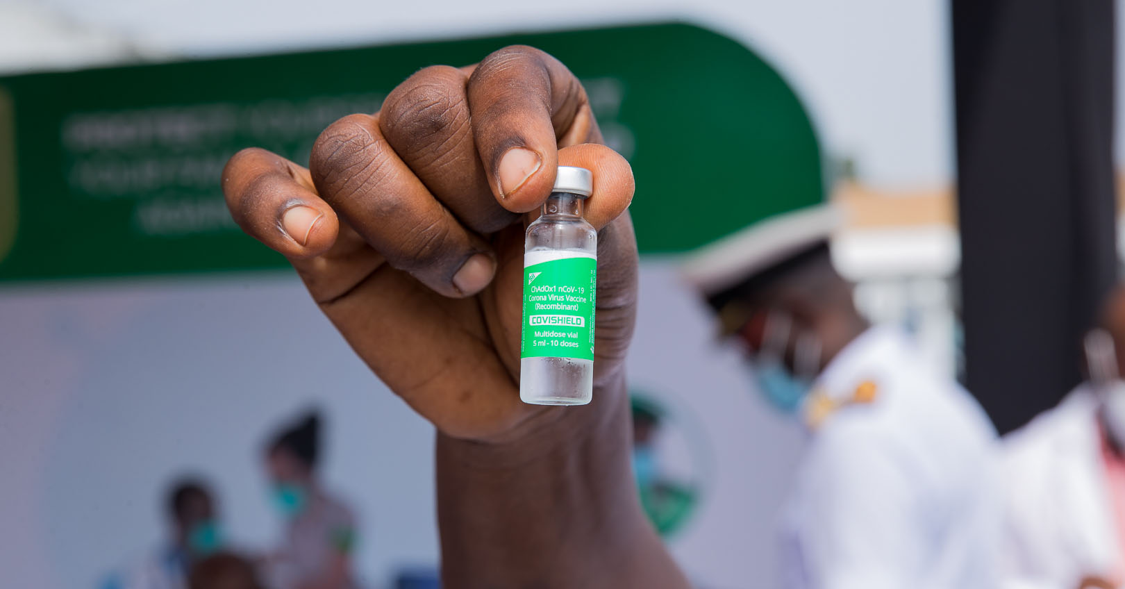 Person's hand holding up a glass vial of Covishield Corona Virus vaccine